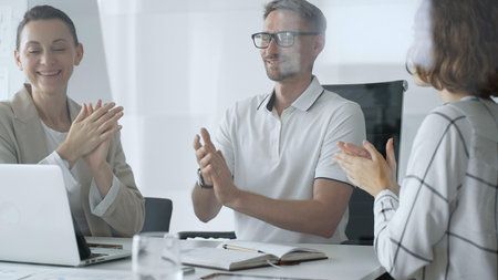 Professional team applauding, celebrating collaborative success and recognizing outstanding performance during corporate meeting in office. Business people conceptの写真素材