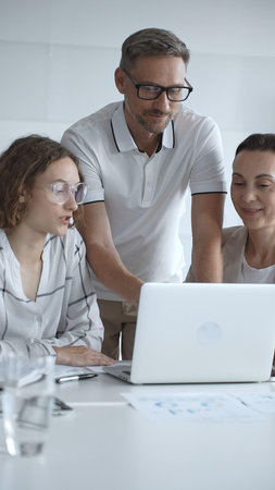 Business people team collaborating and analyzing data on a laptop during an office meeting, uniting...