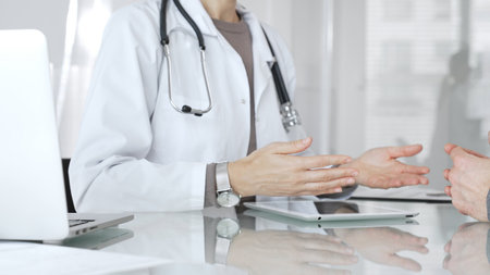 Doctor consulting patient, discussing diagnosis, using digital tablet in modern medical clinic. Medicine and health careの写真素材