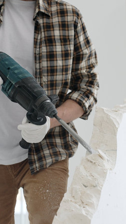 Close up of unknown male construction worker wearing beige checkered shirt and protective gloves, is...