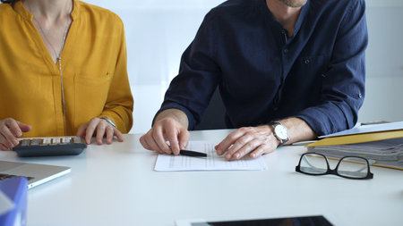 Business people engaging in a discussion about a contract while calculating costs during an office...