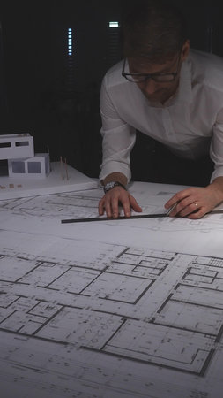 Professional architect working late, drawing blueprints for a new residential construction project....