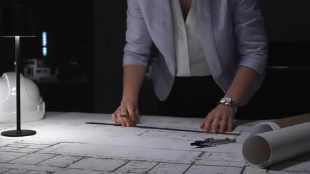 Architect hand drawing building plan, focused on engineering blueprints at office desk, hard hat...