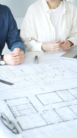 Architects collaborating on architectural project, discussing building design plans, creating new...
