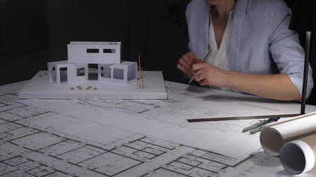 Architect analyzing blueprints and architectural scale model, planning a modern house construction...