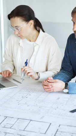 Architects collaborating on architectural project, discussing building design plans, creating new...