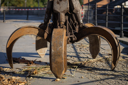 Heavy industrial claw grabber in action, collecting debris and wood on a sunny day. Concept of construction machinery, urban infrastructure maintenance, and industrial equipmentの写真素材