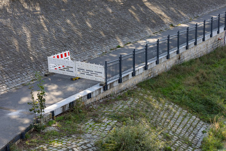 Closed bike path next to river blocked due to flooding after heavy rains. Safety barricades prevent access, highlighting urban flood control, infrastructure, and public safety measuresの写真素材