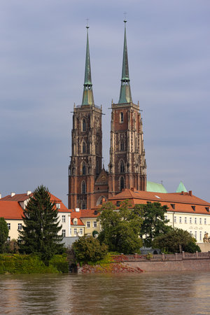 Cathedral in Wroclaw during high water levels on the Odra River. Historic Gothic architecture of twin spires reflecting on floodwater, highlighting climate impact on European citiesの写真素材