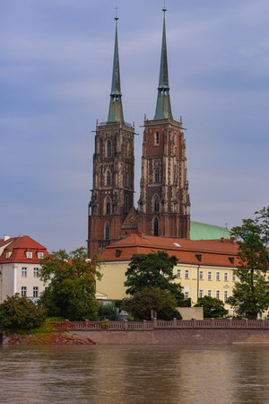 Historic twin-spired cathedral in Wroclaw with rising river water levels after heavy rainfall on a cloudy day. Concept of climate impact and environmental awarenessの写真素材