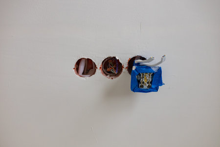 Electrical socket installation in progress with exposed wires and junction box covered in protective...