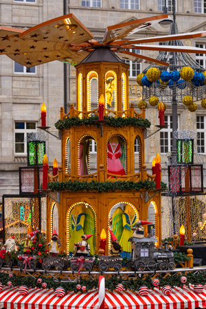 A traditional Christmas pyramid at the Wroclaw Christmas market, decorated with candles, garlands and gnome figures, surrounded by bright festive lights, ornaments and cheerful seasonal decorations.の写真素材