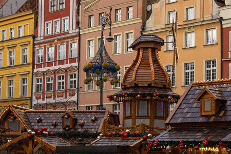 Charming wooden stalls at the Wroclaw Christmas market with festive decorations, glowing lights, traditional architecture and colorful European buildings in the background during the holiday seasonの写真素材