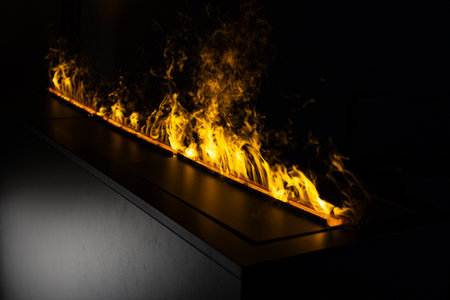 Dramatic close-up of a modern linear ethanol fireplace with bright yellow flames dancing in the dark environment, creating a luxurious atmosphere for contemporary interior design and home decorの写真素材