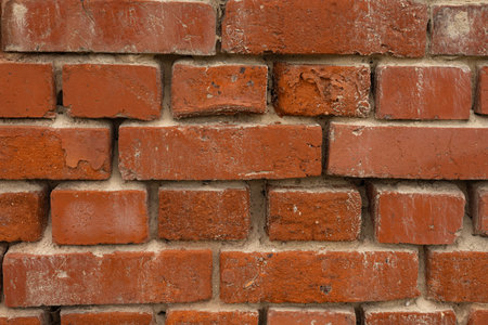 Close-up texture of old red brick wall with weathered surface and visible mortar seams, showcasing industrial charm and timeless architectural details. Perfect for backgrounds and design conceptsの写真素材