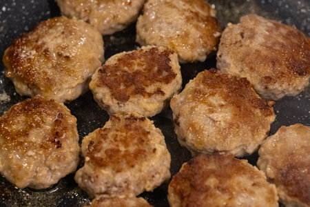 Homemade juicy meat patties frying in a pan with sizzling oil, golden brown crust, and tender texture. Traditional home cooking, comfort food, delicious meal preparation and homemade cuisineの写真素材