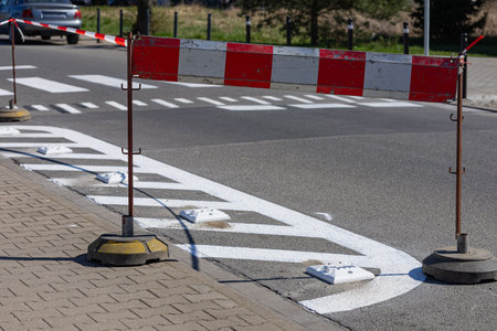Freshly painted road markings with temporary barrier on residential street during improvement of traffic organization and safety. Urban infrastructure upgrade and pedestrian area regulationの写真素材
