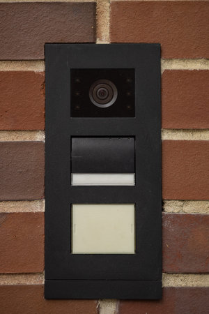 Modern black intercom panel with video surveillance camera, speaker, and nameplate slot mounted on...