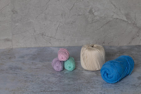 Colorful yarn balls in various shades of blue, green, pink, and white, arranged artistically on a...