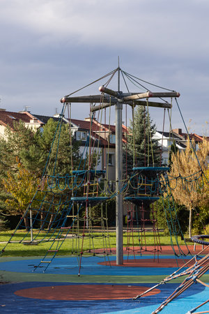 Playground climbing features structure colorful rubber flooring, surrounded by trees and buildings, creating an inviting space for outdoor play and physical activityの写真素材