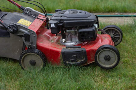 Close up view of red gasoline lawn mower for home yard maintenance and landscaping care. Outdoor...