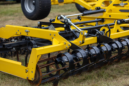 Close up of hydraulic system on yellow agricultural subsoiler with cylinders, hoses and black metal rollers. Modern farming machinery for precise soil preparation in field worksの写真素材