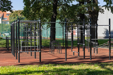 Modern outdoor calisthenics park with pull up bars and parallel bars on a rubber safety surface in a...