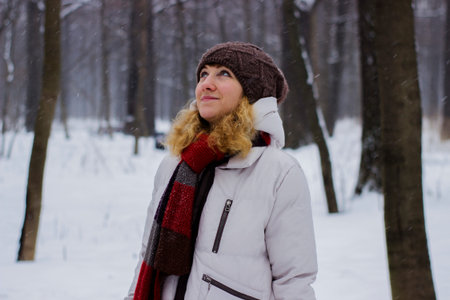 Young beautiful girl close up in winter park enjoys snow fell