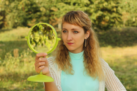 Young beautiful girl look into mirror in the park.Soft and blur conception.の写真素材