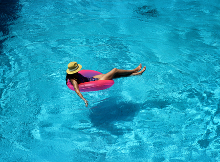Young beautiful girl is swimming in the pool with a pink circleの写真素材