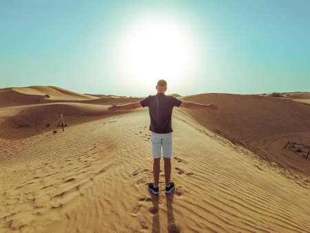 Young beautiful man walks along the sand dunes of the Dubai desert.の写真素材