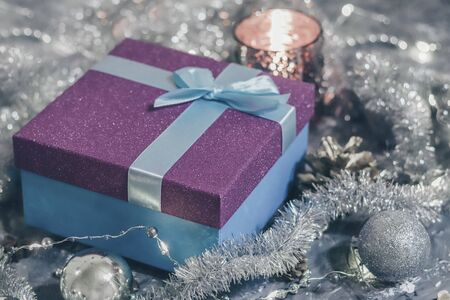 Shiny gift box with gift and holiday decorations on gray background.の写真素材