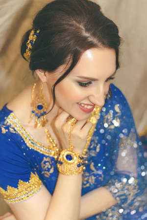 Indian woman cosplay. Young beautiful woman in blue indian sari dress closeup on the multicolored brown background.の写真素材