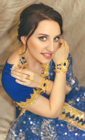 Indian woman cosplay. Young beautiful woman in blue indian sari dress closeup on the multicolored brown background.の写真素材