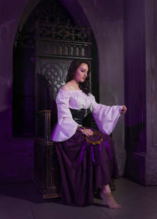 Beautiful gypsy woman closeup in the dark room of cathedral church with music tambourine in her hands.の写真素材