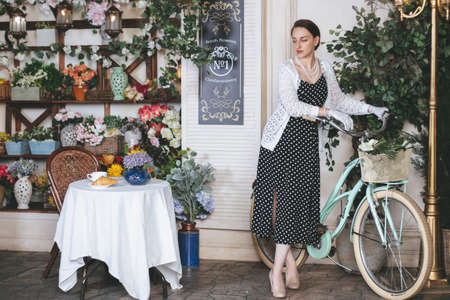 Young pretty woman dressed up into retro style is sitting in the street cafe with cup of coffee and croissant.の写真素材