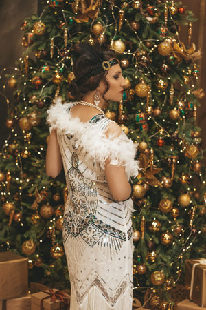 Beautiful woman close up on the decorated fir-tree background.