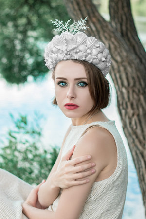 Young beautiful mermaid in seashells crown is sitting on the water background.Mermaid cosplayの写真素材