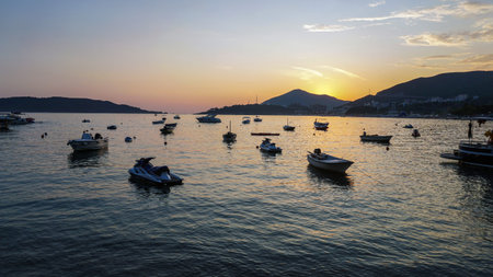 Small boats. Beautiful sunset at the sea. Mountains in the background.