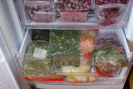 Open freezer with frozen red cherries and frozen vegetables. Food storage. Frozen food. Stocks of products for the quarantine period.の写真素材