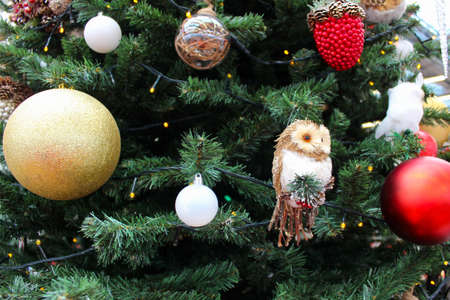 Christmas tree with Christmas decorations: colorful balls, lights, a toy owl, cones, berries.の写真素材