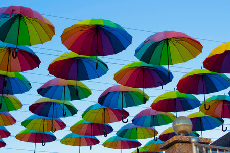 Many colorful umbrellas hang in the sky above the cafe. Decorating the street with umbrellas.