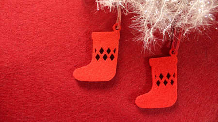 Christmas decoration: Christmas tree toy made of red felt in the form of a Christmas sock for gifts. Socks on a red background with white shiny snow.の写真素材