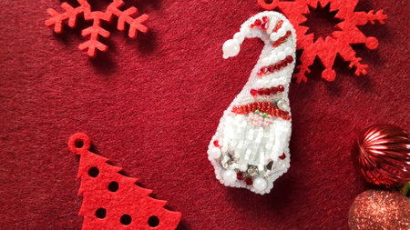 Christmas gnome with Christmas toys on a red background. Womens brooch embroidered with beads Christmas gift. Christmas symbol.の写真素材