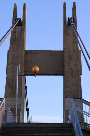 Concrete supports for a suspended pedestrian bridge with cables. Staircase upstairs. Rectangular...