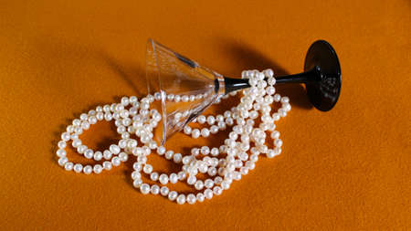 Pearl necklace in a martini glass on a yellow background and copy space. Decoration for a woman.の写真素材