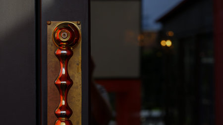 A glass door with a shiny doorknob and a lock for exiting the city street. Evening lights of the city behind the glass of the door. Late evening.の写真素材