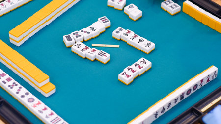 A mahjong table with an active game. An ancient Asian game called Mahjong as a way to relax and have fun. Many Mahjong tiles on on the playing field.の写真素材