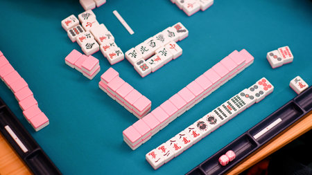 A mahjong table with an active game and the hands of a participant in the game. An ancient Asian game called Mahjong as a way to relax and have fun. Fragment of the game.の写真素材