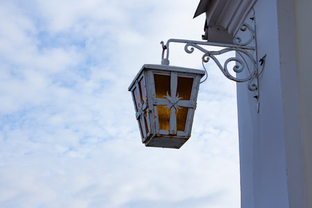 An old lantern on the wall of an old house against the blue sky. A decorative element of a city street.の写真素材